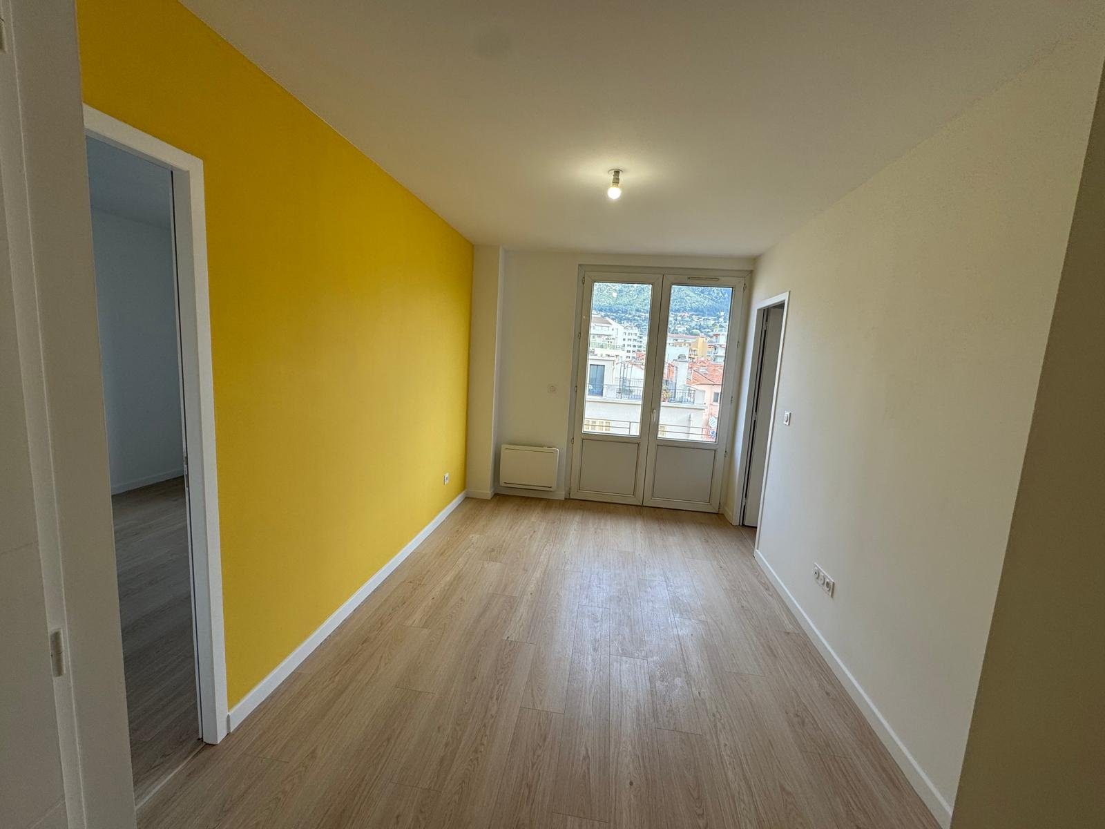 Pièce rénovée avec mur jaune et parquet