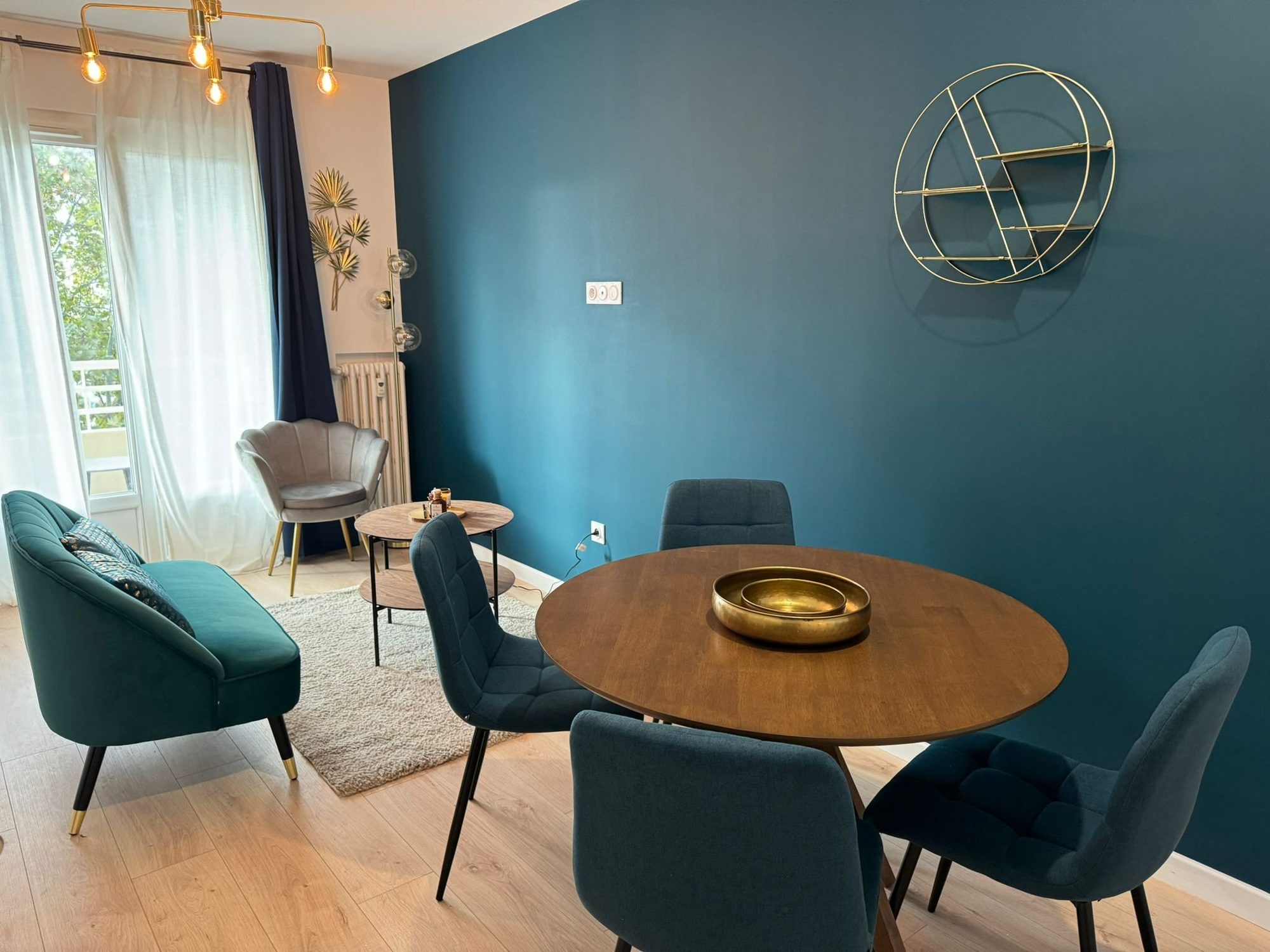 Séjour rénové avec mur bleu canard et table ronde